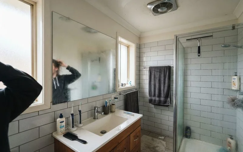 A bathroom exhaust fan running above a shower, with steam visibly clearing from the room during and after use